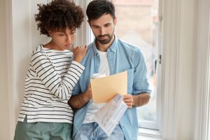 Une personne consulte des annonces de logements sur un ordinateur portable, avec son dossier de candidature posé à côté.