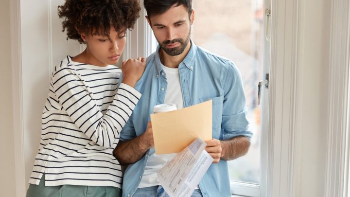 Une personne consulte des annonces de logements sur un ordinateur portable, avec son dossier de candidature posé à côté.