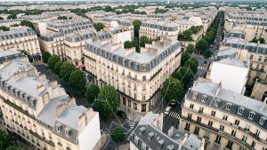 Vue aérienne réaliste d’une ville française aux immeubles anciens, avec des éléments immobiliers discrets superposés.